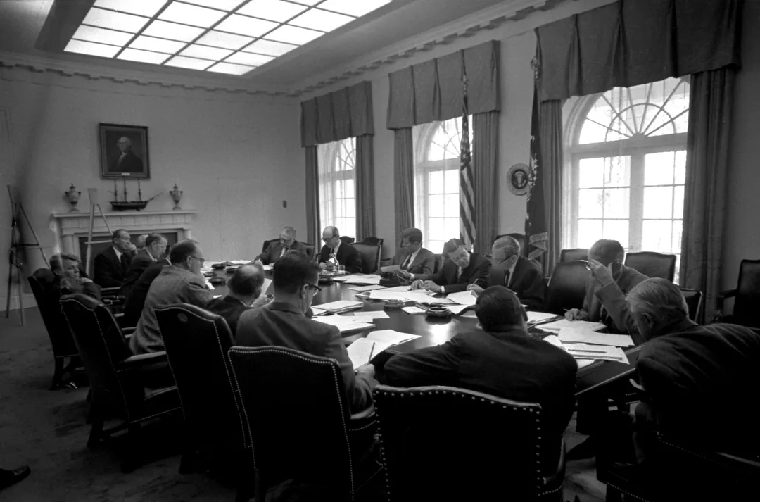 Black-and-white photo of some twenty men in suits at a long table in the Cabinet Room